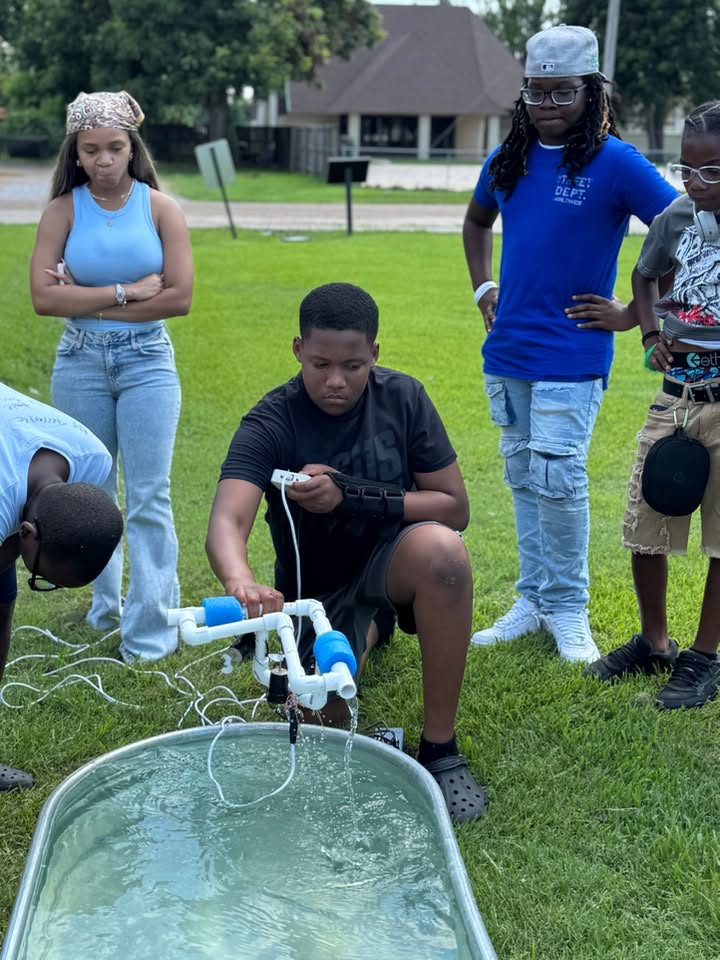 A boy putting some kind of floating device with wires attached into a tub of water.